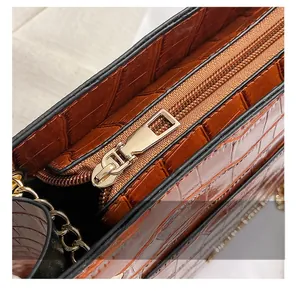 Détail d'une fermeture éclair en métal doré sur un sac en cuir marron à texture crocodile