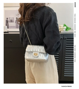 Close-up of a silver quilted crossbody bag with a gold turn-lock and elegant chain strap