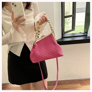 Detail of rose pink knitted shell bag featuring metal clasp and chunky gold chain