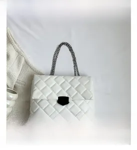 Detailaufnahme der weißen Stepptasche mit Metallschild-Verschluss und Kettenriemen