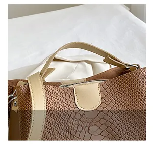 Close-up of brown crocodile embossed tote bag with beige handles and zipper closure