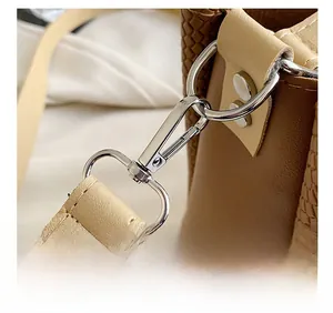Detail of silver metal hook and D-ring on brown croc-embossed and beige leather bag