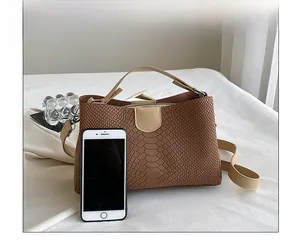 Brown textured PU leather tote bag shown with a smartphone for size comparison