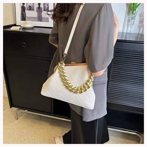 Detail of white woven shell bag featuring a chunky gold chain handle and metal clasp