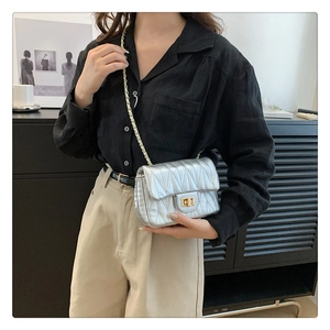 Detail of silver quilted crossbody bag with golden chain strap and metallic twist lock