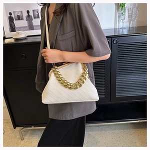 Detailed view of white textured shell bag with chunky gold chain and metal clasp