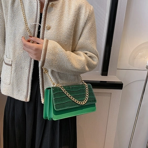 Sac à bandoulière vert motif crocodile avec chaîne dorée porté sur l'épaule