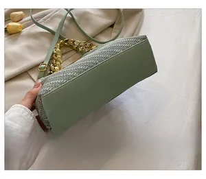 Detail shot of mint green handbag featuring herringbone weave fabric and gold chain strap