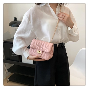 Detail of pink quilted crossbody bag with gold twist lock and chain strap on model