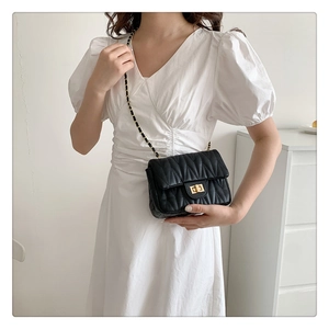 Detail of black quilted leather shoulder bag with V-shaped stitching and gold metal twist lock