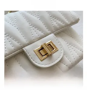 Detail of white quilted leather crossbody bag with elegant gold metal twist-lock buckle