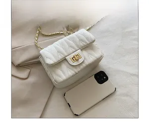 Detailed size comparison of a white quilted chain bag with a smartphone on beige fabric