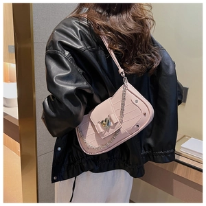 Detailed shot of trendy pink crocodile pattern shoulder baguette bag with chic heart clasp.