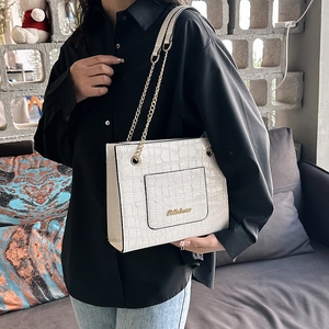 Sac fourre-tout blanc cassé à texture crocodile avec bandoulière chaîne dorée sur mannequin