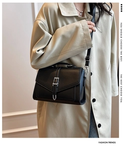 Detail of black leather crossbody bag with silver buckle and adjustable shoulder strap