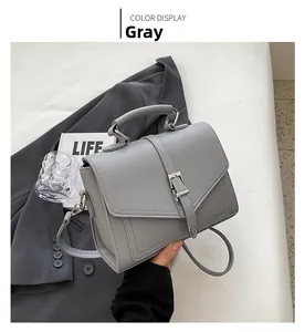 Detail view of grey flap shoulder bag with metallic buckle and detachable strap