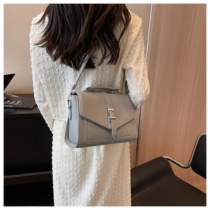 Detailed view of gray pebbled leather handbag worn as a stylish crossbody on shoulder