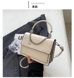 Dettaglio della borsa beige quadrata con catena d'argento e testo FASHION & BAGS su blazer