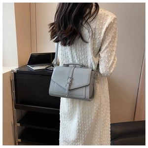Litchi texture gray crossbody bag with silver buckle worn by a model in a modern office