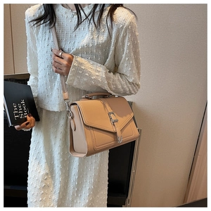 Detail of minimalist beige flap handbag featuring textured faux leather and metal buckle strap