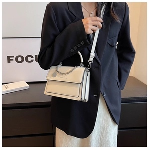 Dettaglio borsa a mano crema con ciondolo a catena argento e scritta Fashion & Bags