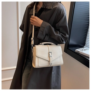 Detail of cream-colored lychee leather crossbody bag with metallic buckle on female model