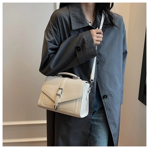 Detail of a beige vintage crossbody bag showing faux leather texture and metallic buckle