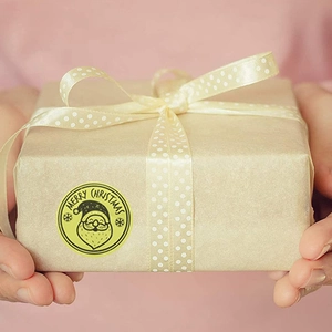 Golden Merry Christmas stickers with Santa Claus motif on kraft paper gift package