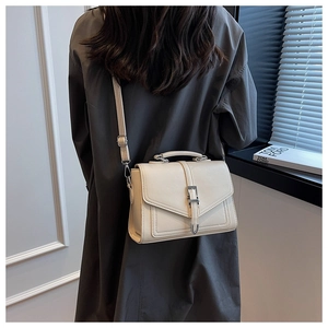 Close-up of cream textured leather handbag with silver buckle and detachable shoulder strap