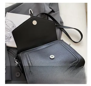 Detail shot of the magnetic snap closure on a black pebbled leather crossbody bag