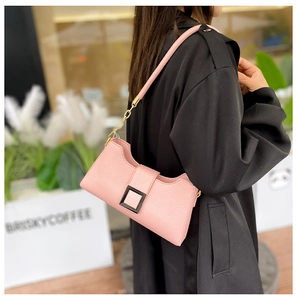 Dettaglio borsa a spalla in pelle martellata rosa chiaro con catena dorata su cappotto