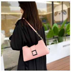Dettaglio ravvicinato della borsa sottobraccio in pelle martellata rosa e catena oro