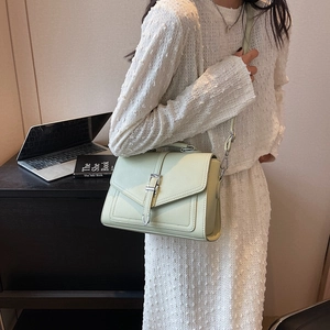 Pale green pebble leather crossbody bag with silver hardware on a desk background