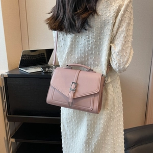 Elegant dusty pink crossbody bag with litchi texture and metal buckle on home background