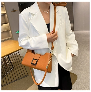 Borsa a spalla marrone con grana litchi e fibbia quadrata su un blazer bianco elegante