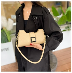 Dettaglio borsa a tracolla in pelle beige con fibbia in metallo e tracolla a catena dorata