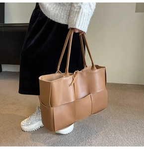 Detailed close-up of brown woven leather texture on a large capacity tote bag