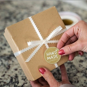 Kraft paper gift box with white lace ribbon and handmade sealing sticker on marble background