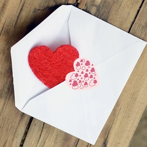 Valentine heart decorations and pink card in a white envelope on wooden background