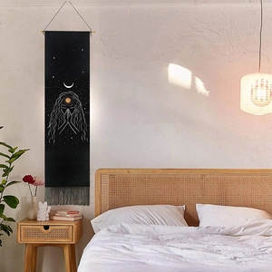 Bohemian black wall tapestry with moon sun motifs and gray tassels in a cozy bedroom