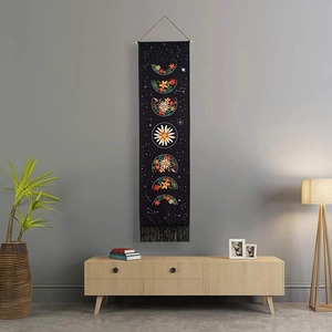 Bohemian floral moon phase tapestry with black fabric and decorative fringe hanging on a wall