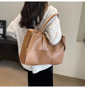 Detailed shot of large woven caramel tote bag in soft leather showing its texture and size