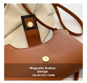 Dettaglio della chiusura magnetica di una borsa a tracolla a mezzaluna in pelle marrone