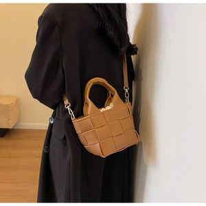 Dettaglio della trama in pelle intrecciata di una borsa a tracolla marrone con coulisse