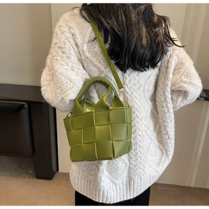 Dettaglio borsa intrecciata verde con tracolla staccabile e sacchetto interno con cordoncino