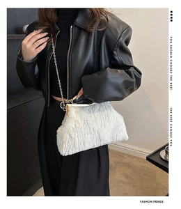 Close-up of white plush evening bag with textured fur, metal frame and gold chain strap