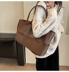 Close-up of brown woven leather tote bag shoulder strap and textured weave pattern