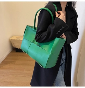 Close-up of green woven leather tote bag with wide weave detail on female model
