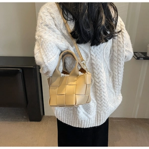 Dettaglio di una borsa a secchiello in pelle intrecciata beige con design a griglia moderna