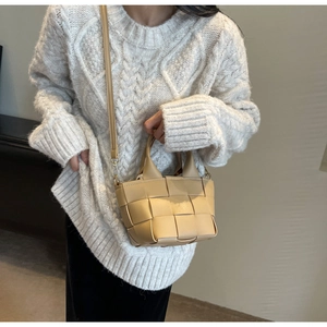 Dettaglio borsa intrecciata beige con finiture dorate e tracolla staccabile